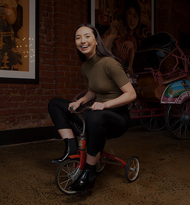 Woman riding small red tricycle